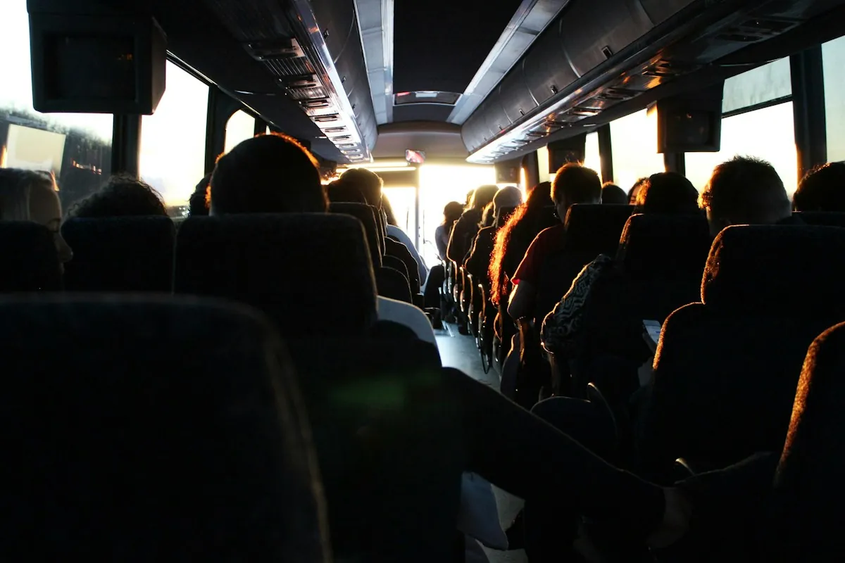 Passeggeri seduti in un pullman, visti da dietro in controluce