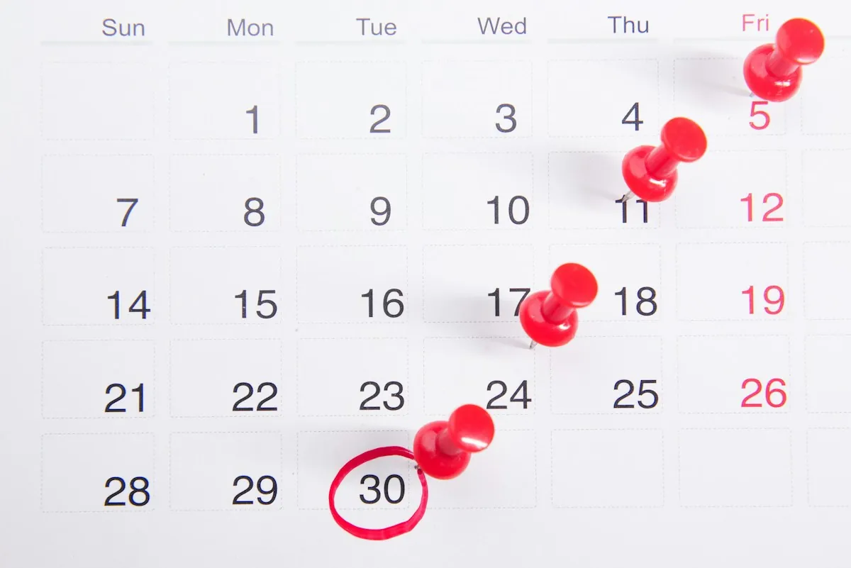 Un calendario da parete con alcune date segnate da puntine