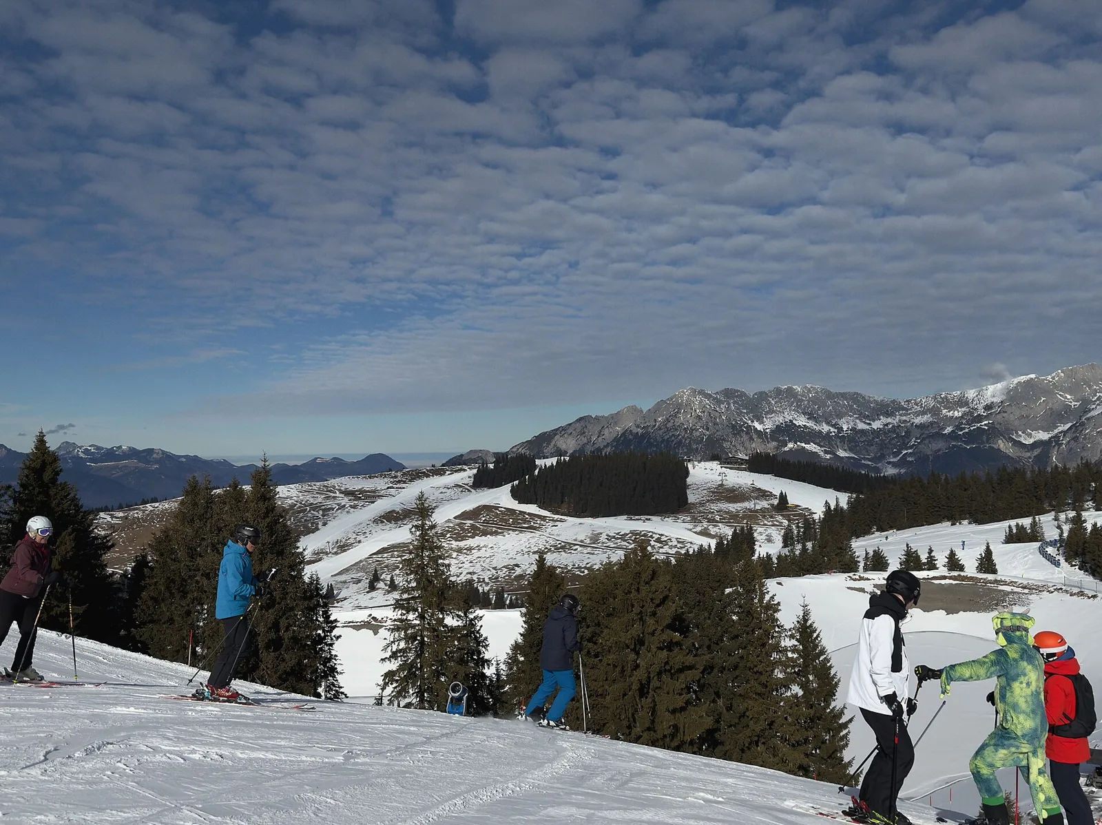 Sciatori su una pista innevata con le montagne del Kaiser sullo sfondo, in Austria