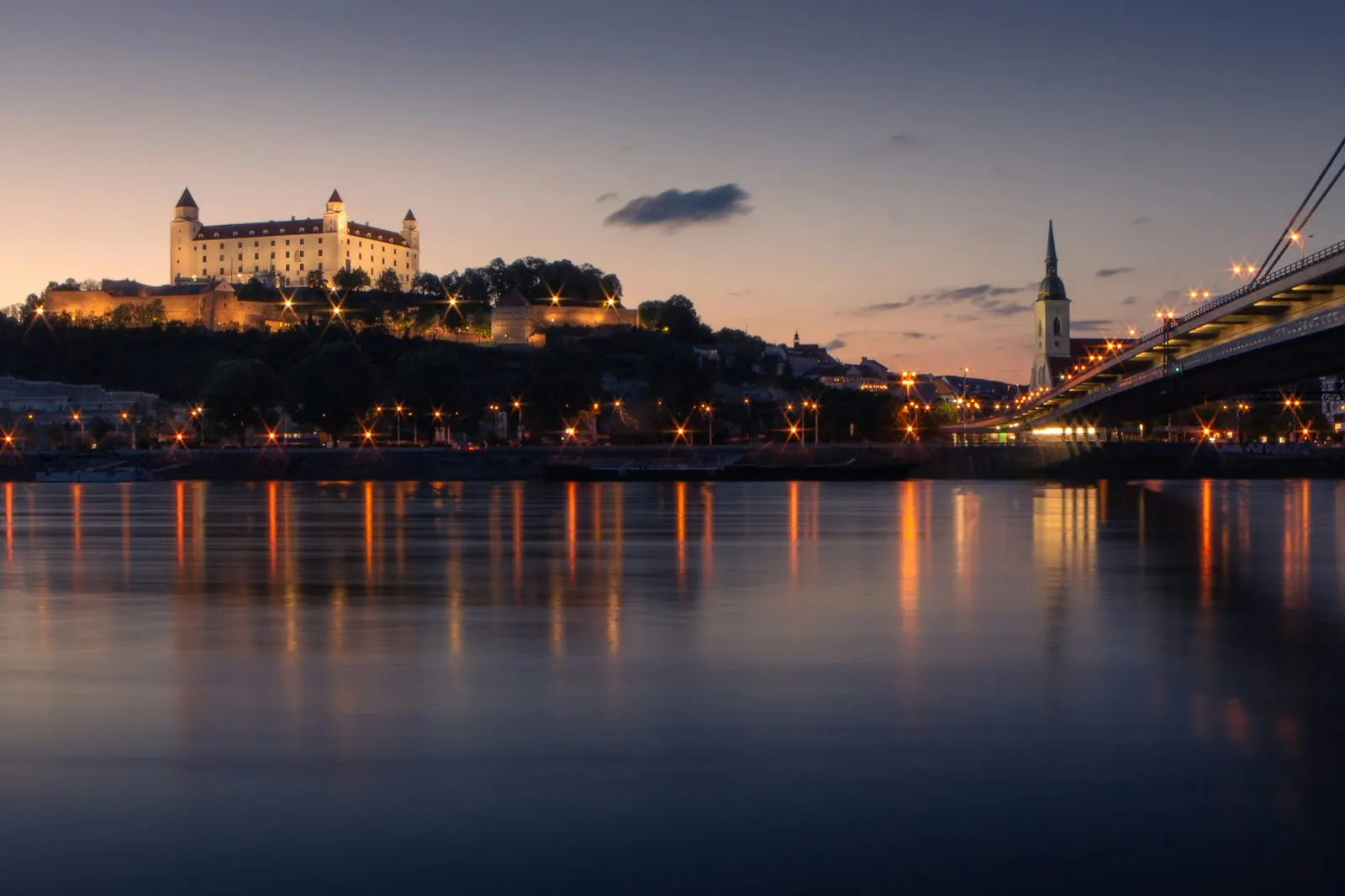 Il castello di Bratislava illuminato di sera sul Danubio